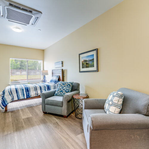 Model bedroom with natural lighting and seating area near bed